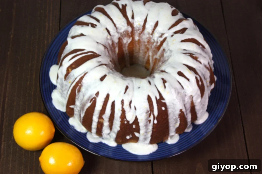 A beautiful Meyer Lemon Bundt Cake on a cake stand, garnished with fresh lemon slices and zest, hinting at the vibrant citrus flavor. It's perfectly glazed and ready to be served.