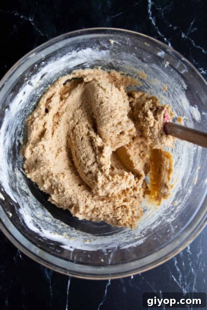 Peanut butter cookie dough in a clear glass mixing bowl, perfectly mixed.
