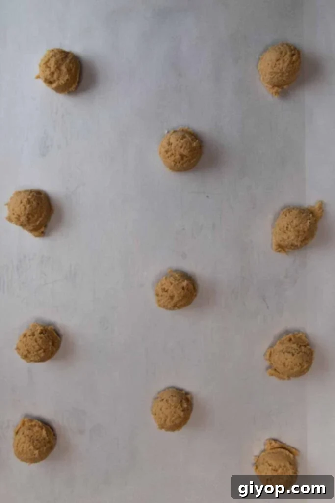 Cookie dough balls evenly spaced on a parchment-lined baking sheet.