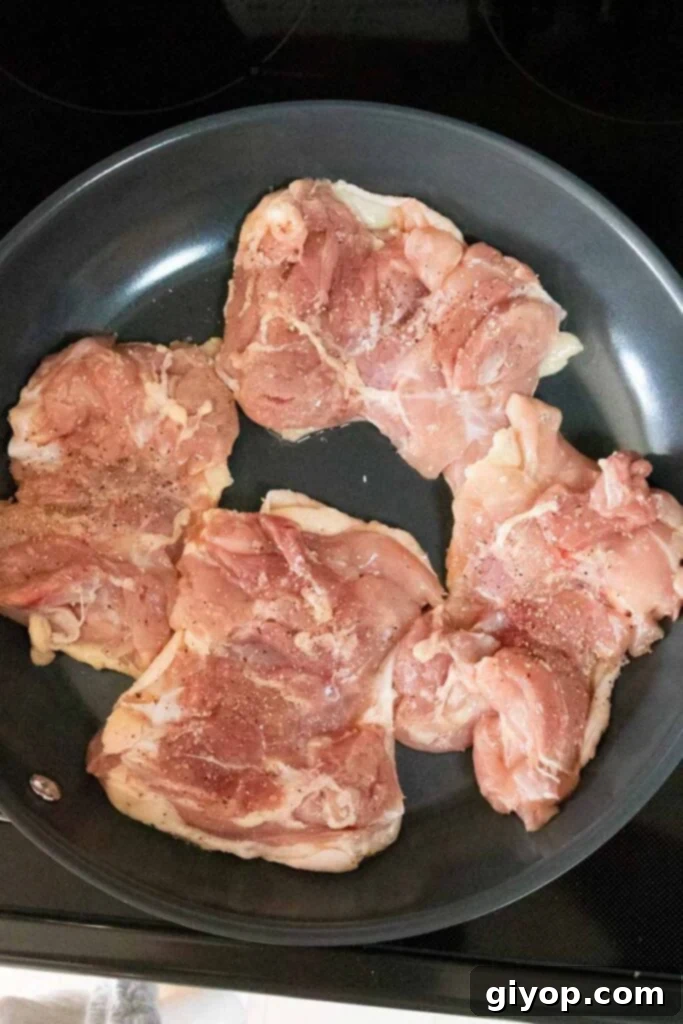 Sticky Crispy Teriyaki Chicken Thighs 5 Raw chicken thighs arranged skin-side down in a cold skillet, ready for cooking.