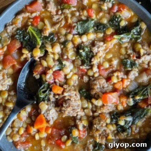Lentil soup with sausage and spinach in a dark bowl.