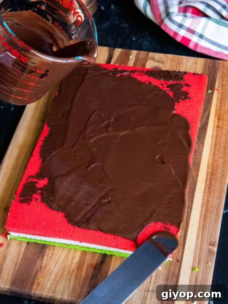 Chocolate being spread over the red cookie layer.