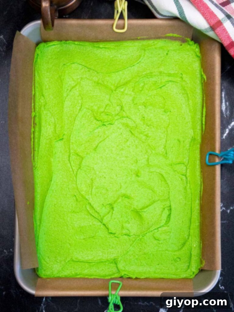 Green cookie dough in the parchment paper lined pan.