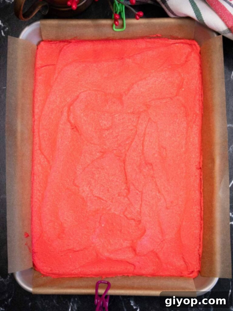 Red cookie dough in the parchment paper lined pan.