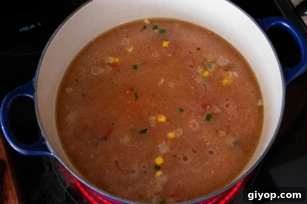 Comforting Stovetop Chicken Tortilla Soup 4 A beautiful blue dutch oven filled with the initial ingredients for chicken tortilla soup, simmering gently.