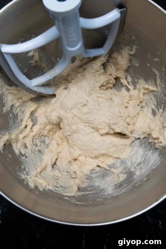 Actively rising dough in a stand mixer bowl.