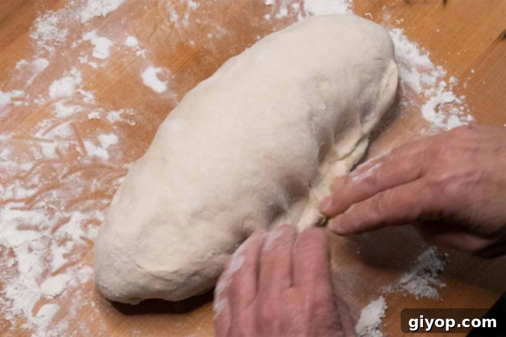 Creating a sealed seam on the underside of the bread dough loaf.