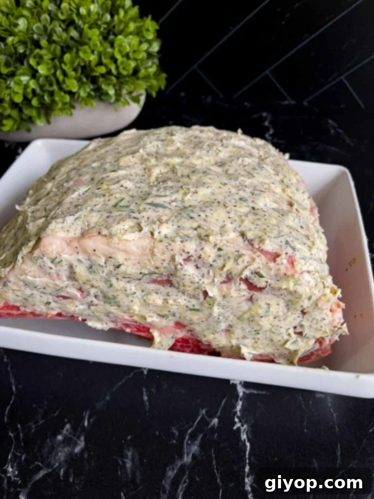 Prime rib coated in a butter compound placed in a shallow roasting pan.