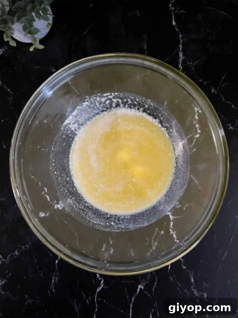 Melted butter in a glass mixing bowl on a dark surface, glistening and ready for other ingredients.