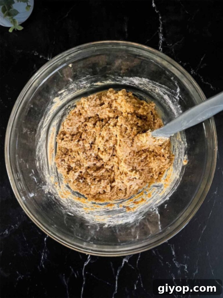 Peanut butter pretzel bar mixture in a glass mixing bowl on a dark surface, blended and ready to be pressed.