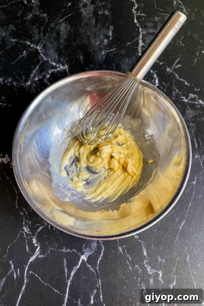 Honey butter in a stainless steel bowl with a whisk.