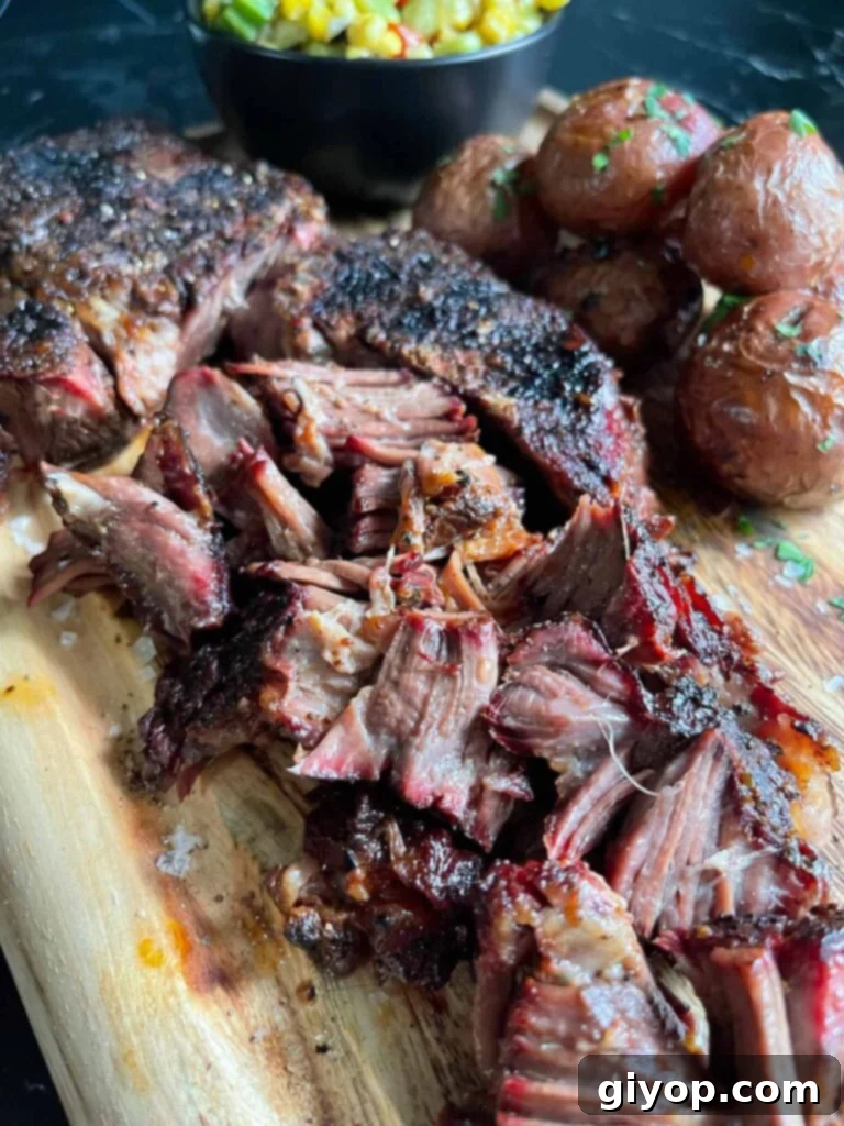 Smoked chuck roast with some grilled potatoes and succotash on a wooden board.