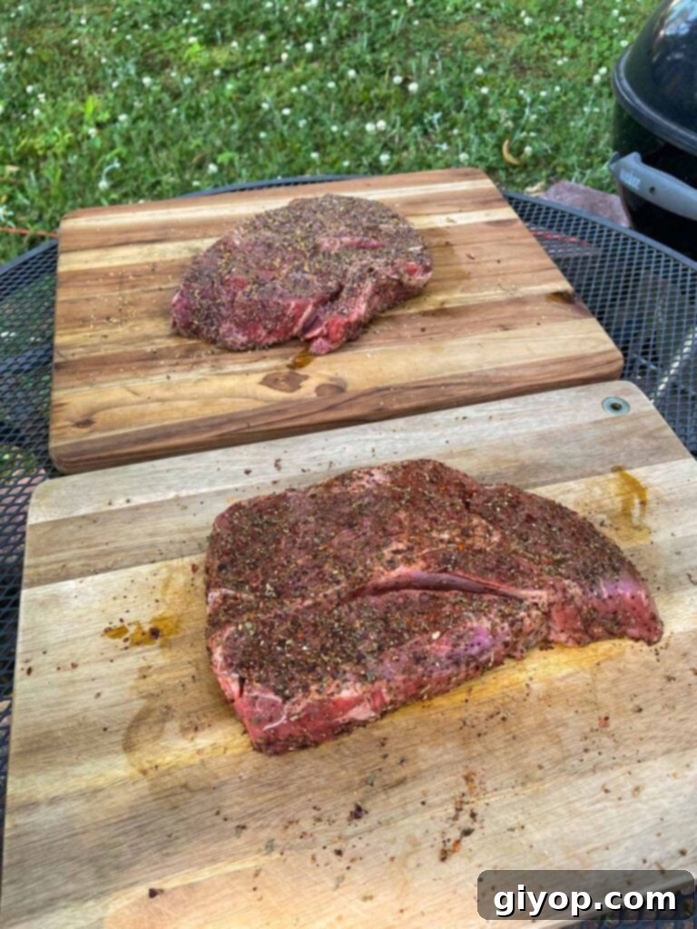 two chuck roasts with rub applied about to go onto a smoker.