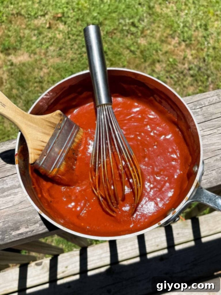 Homemade bbq sauce simmering in a saucepan, resting on a deck rail.