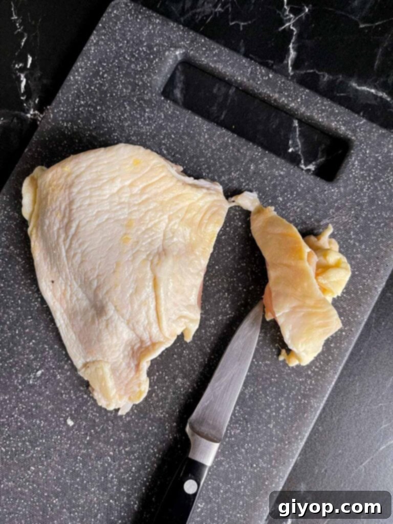 Trimming a chicken thigh.