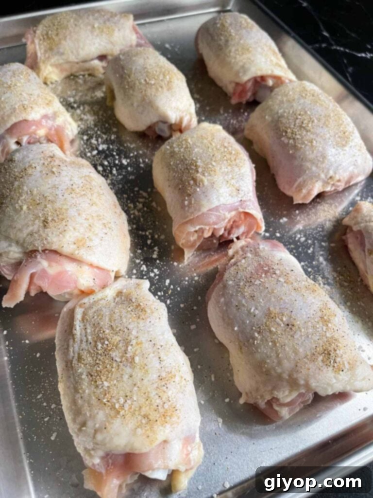 A tray of raw chicken thighs seasoned.
