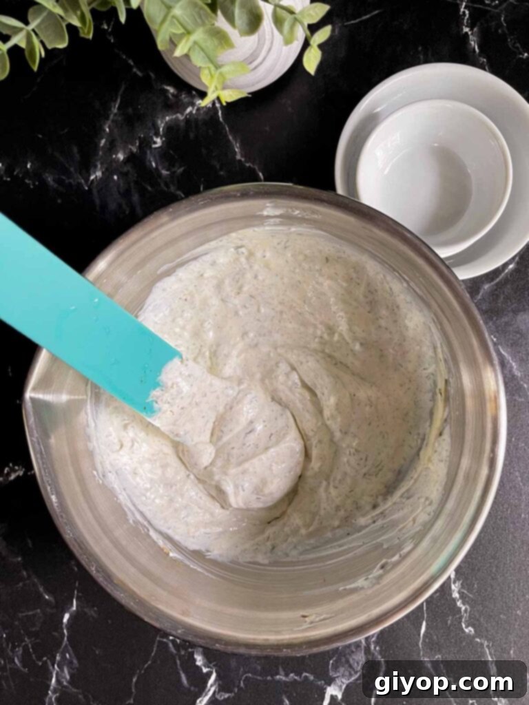 The Ultimate Chip Dip 4 All ingredients for the chip dip, including mayonnaise, sour cream, and dried herbs, combined in a large metal mixing bowl