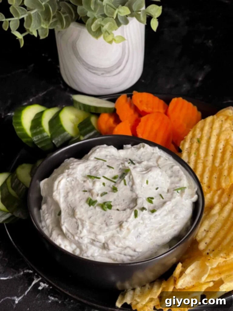 The Ultimate Chip Dip 6 A beautifully arranged spread featuring homemade chip dip in a black bowl, surrounded by various dipping options like potato chips, carrot sticks, and cucumber slices