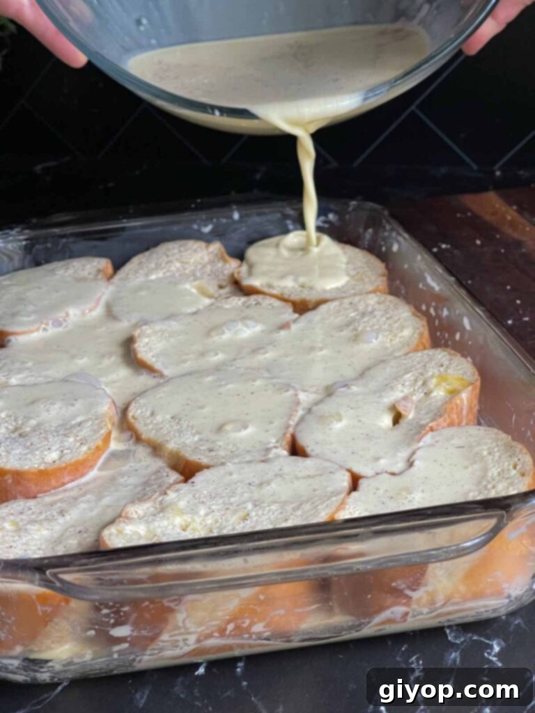Pouring the remaining creamy egg mixture over arranged bread slices in a baking dish, preparing for overnight refrigeration.