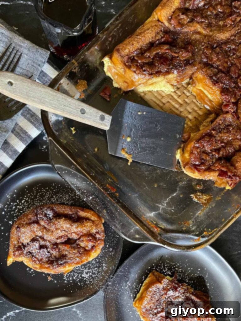 A serving of maple bacon baked French toast being gently lifted from the baking dish, ready for garnishing and serving.