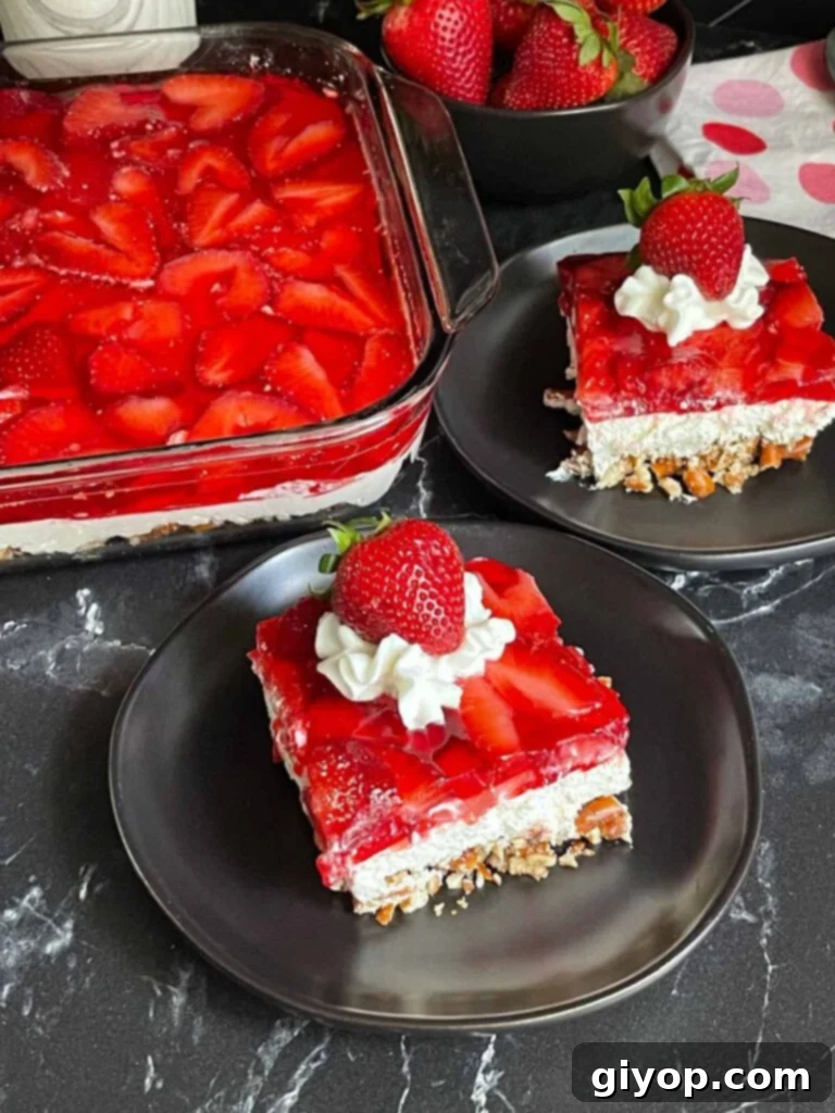 Multiple slices of strawberry pretzel salad served on black plates, showcasing its vibrant layers.
