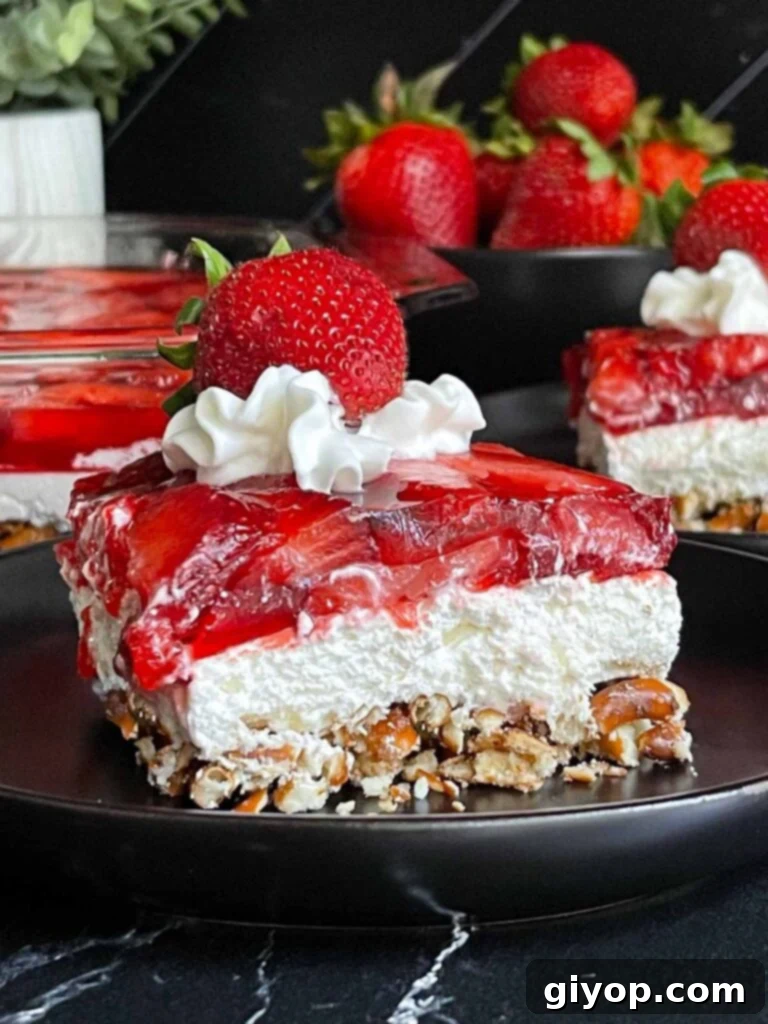 A beautiful, individual slice of Strawberry Pretzel Salad presented on a sleek black plate.