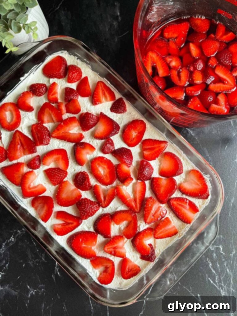 Fresh strawberry slices arranged neatly on top of the whipped cream and cream cheese layer.
