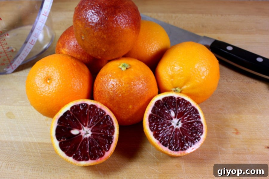 Freshly washed blood oranges arranged on a rustic wooden cutting board, ready for juicing.
