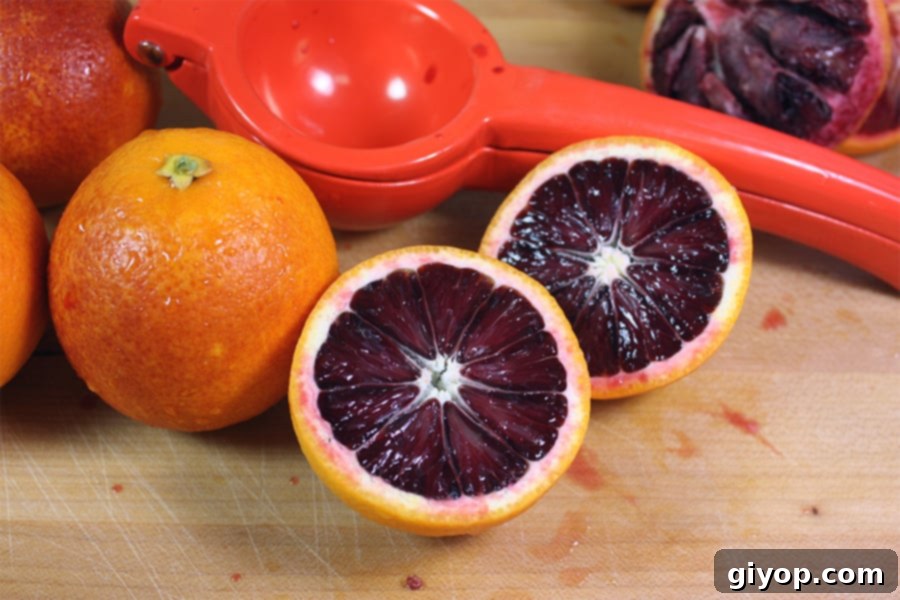A perfectly halved blood orange revealing its stunning crimson flesh, ready for juicing.