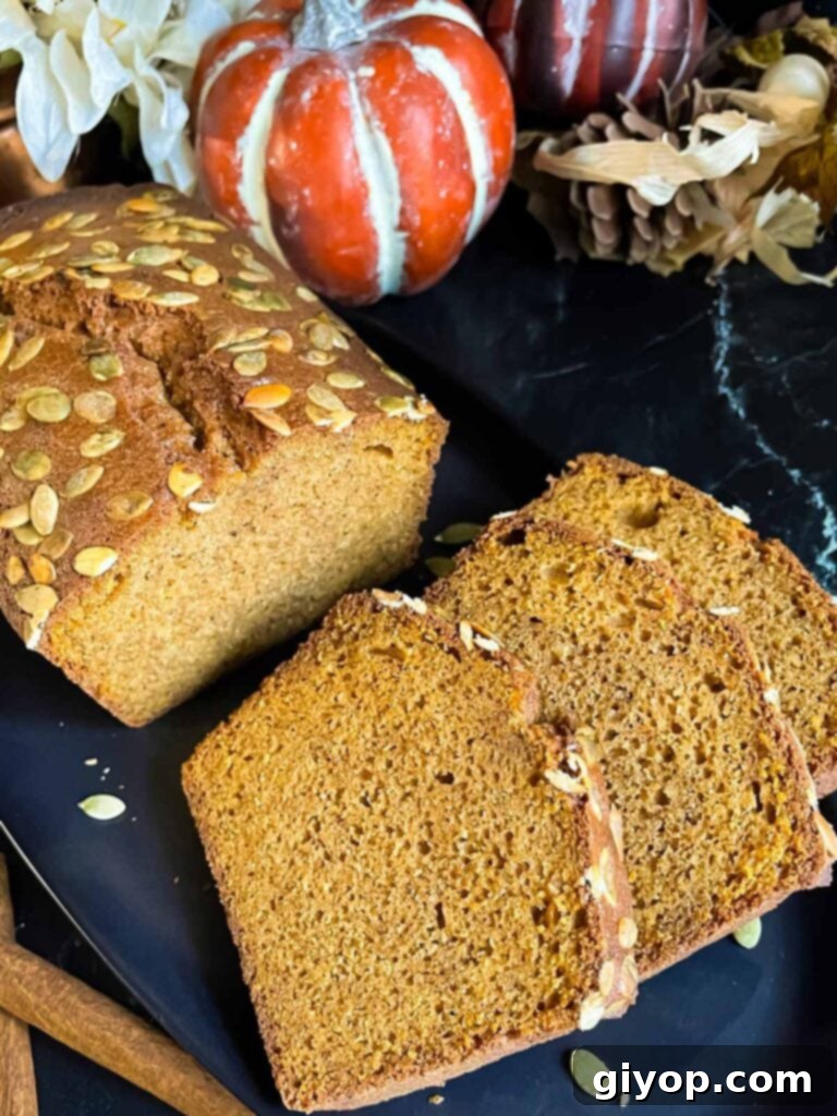 Baked pumpkin bread, sliced, on a dark platter.