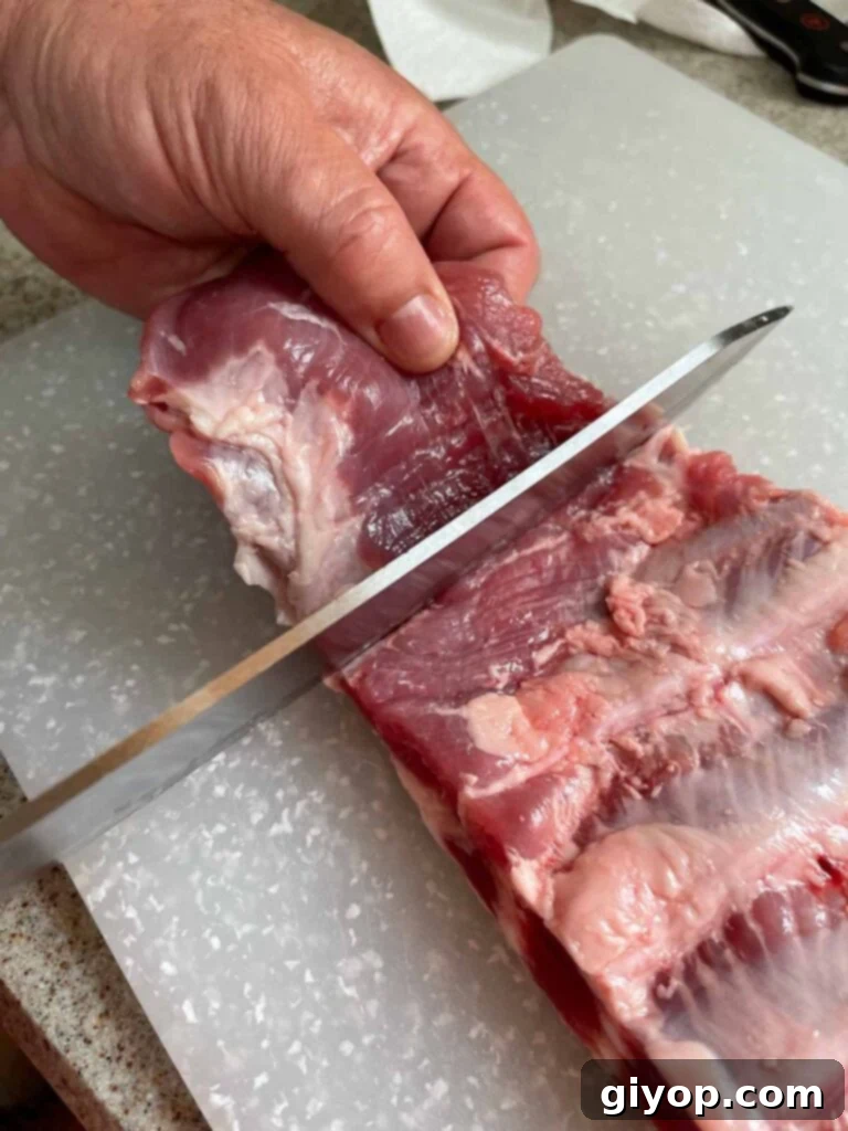 Squaring off the rack of ribs by trimming a small flap of meat.