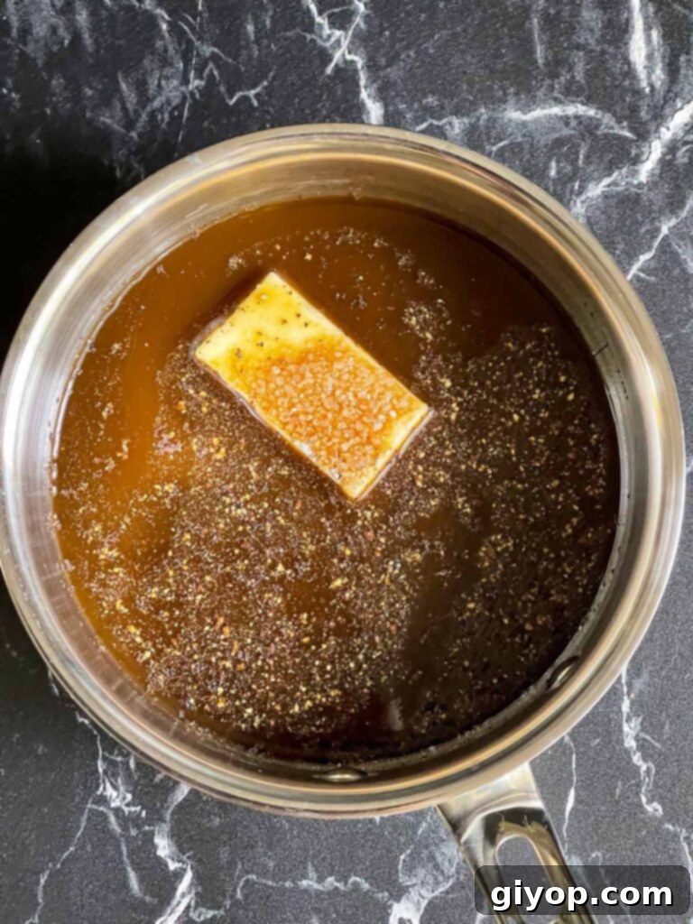 The mop ingredients, including Worcestershire sauce, butter, apple cider vinegar, salt, and pepper, warming in a saucepan.