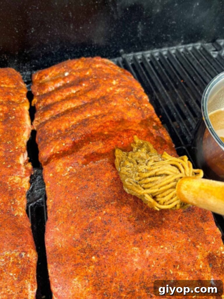 Applying the mop sauce to St. Louis ribs directly on the smoker.