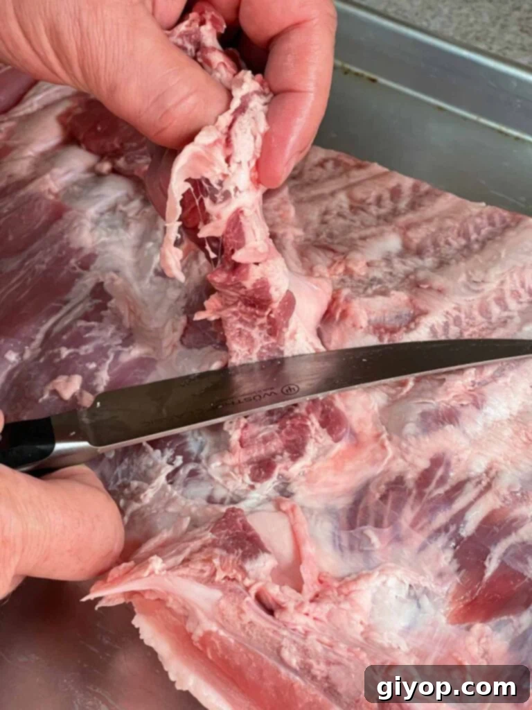 Expertly trimming the diaphragm from the back of a rack of ribs.