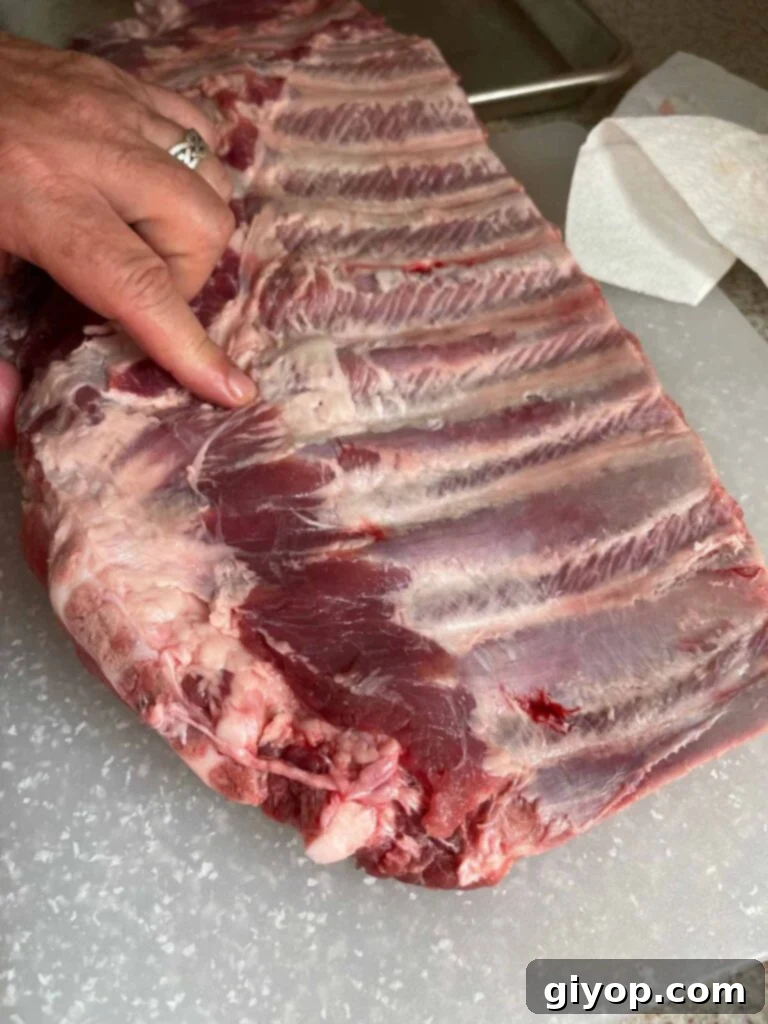 Identifying the precise cut line to remove the brisket bone from a rack of spare ribs.