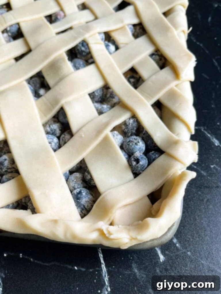 Blueberry Harvest Delight 9 A detailed close-up shot of the corner of a meticulously crafted lattice crust, highlighting the neat weaving and crimped edges of the blueberry slab pie.