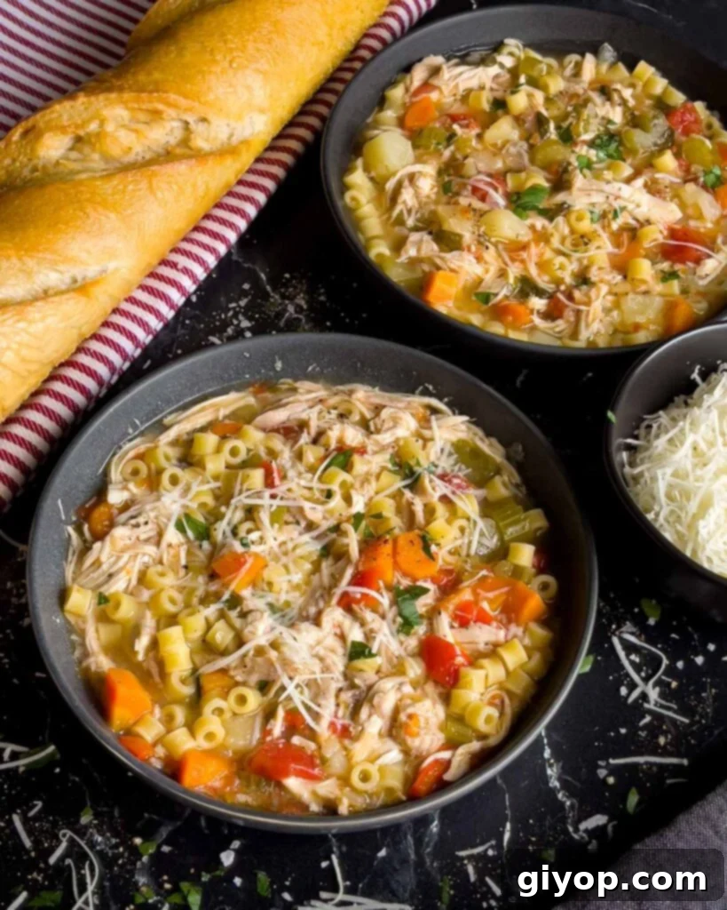 Sicilian Chicken Noodle Soup in a large cup with a parsley and Romano cheese garnish.