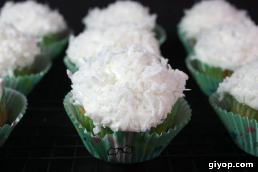Delicious coconut cupcakes on a sleek black background, beautifully garnished with shredded coconut.