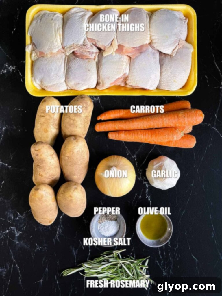 Assorted fresh ingredients for one-pan roasted chicken and vegetables laid out on a dark kitchen counter: raw chicken thighs, whole potatoes, carrots, onions, garlic, and a sprig of rosemary.