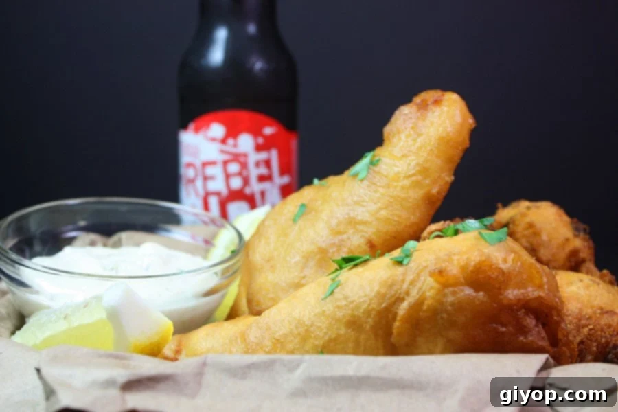 Crispy Beer Battered Fish in a basket with a beer in the background.