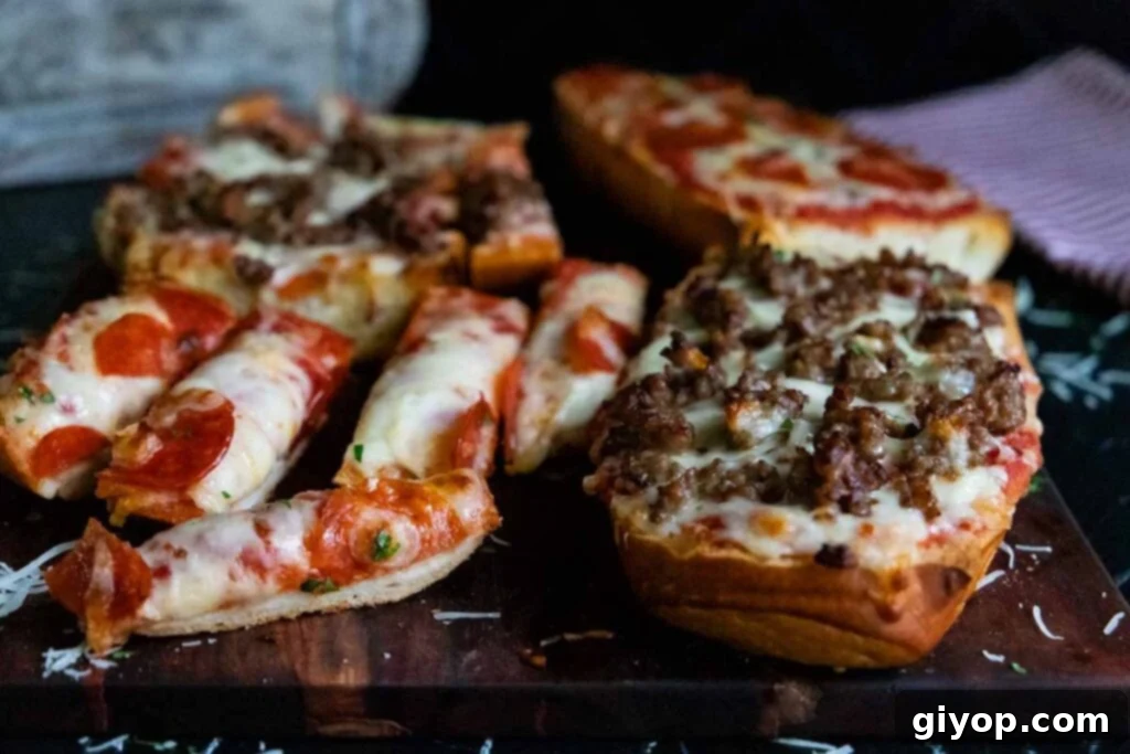 Two halves of French bread pizza, one with pepperoni and the other with Italian sausage, on a rustic wooden cutting board.