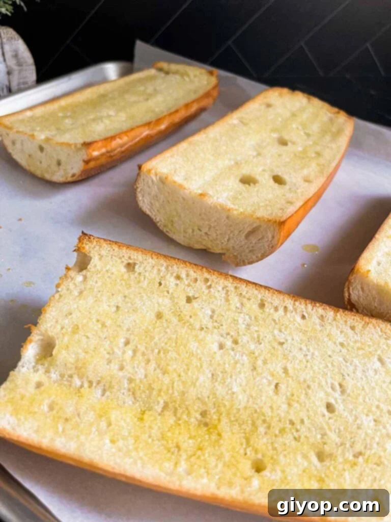 Lightly toasted French bread halves on a baking sheet, ready for pizza toppings.