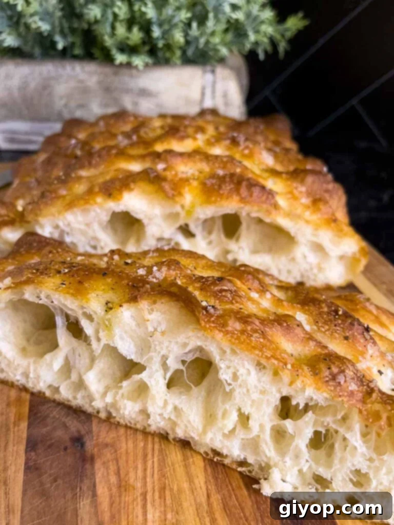 Close-up of freshly cut focaccia bread revealing its dimpled surface and crusty edges on a wooden board.