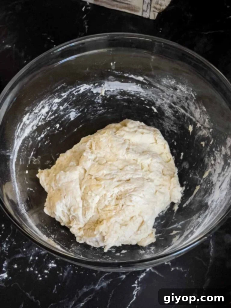 The focaccia dough immediately after mixing, shaggy and sticky in a glass bowl.