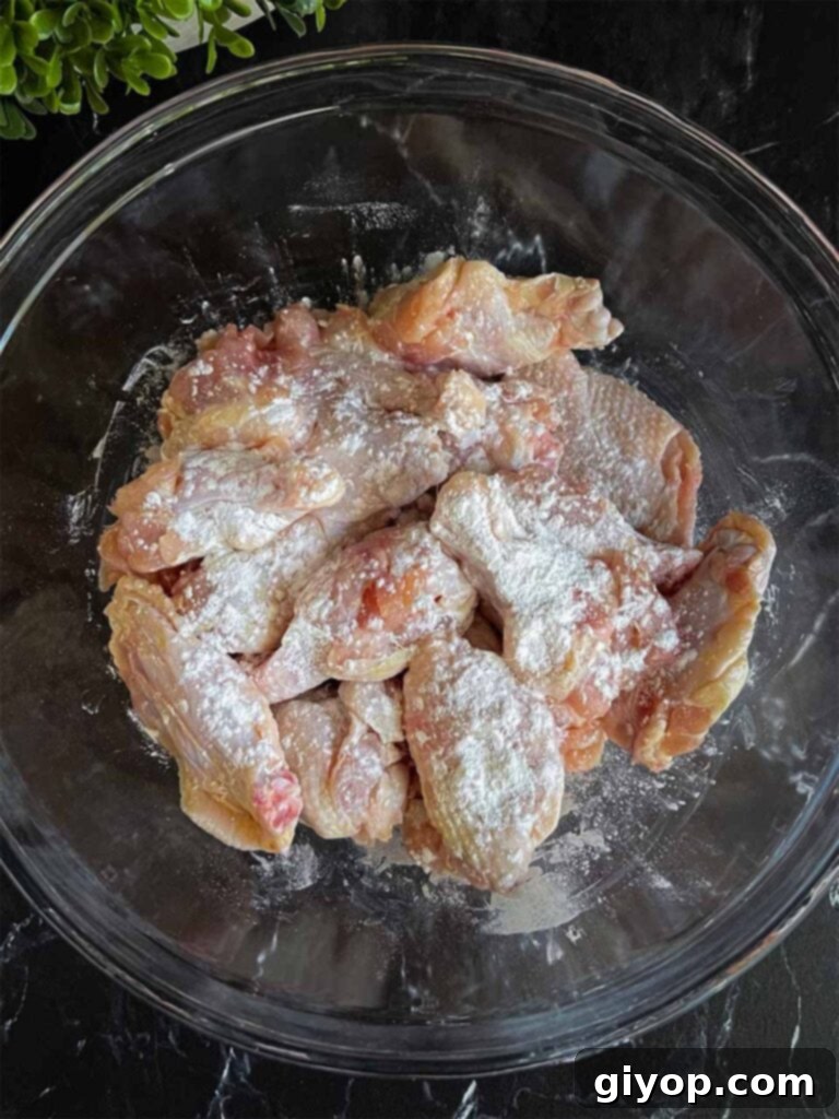 Golden Crispy Asian Oven Wings 4 Raw chicken wings in a glass bowl, lightly coated with baking powder and salt.