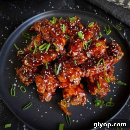Golden Crispy Asian Oven Wings 10 A plate of Asian chicken wings garnished with green onions and sesame seeds.