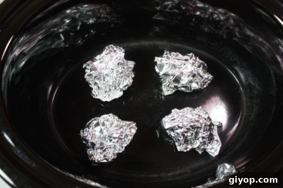 Small balls of aluminum foil used as a rack in the crock of a slow cooker.