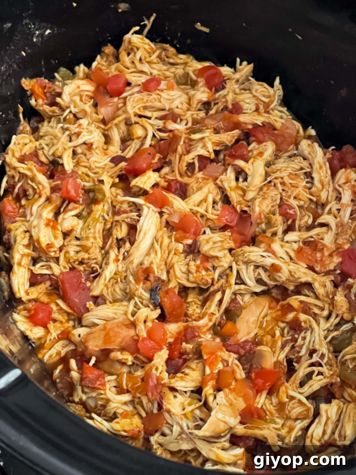 Shredded Mexican chicken in the crock of a slow cooker.