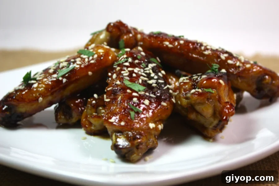 Honey Sriracha Wings on a white plate and a sesame garnish.