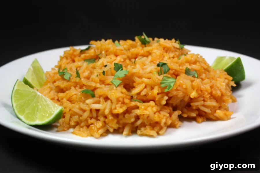 Restaurant style Mexican rice on a white plate with lime wedges as a garnish.